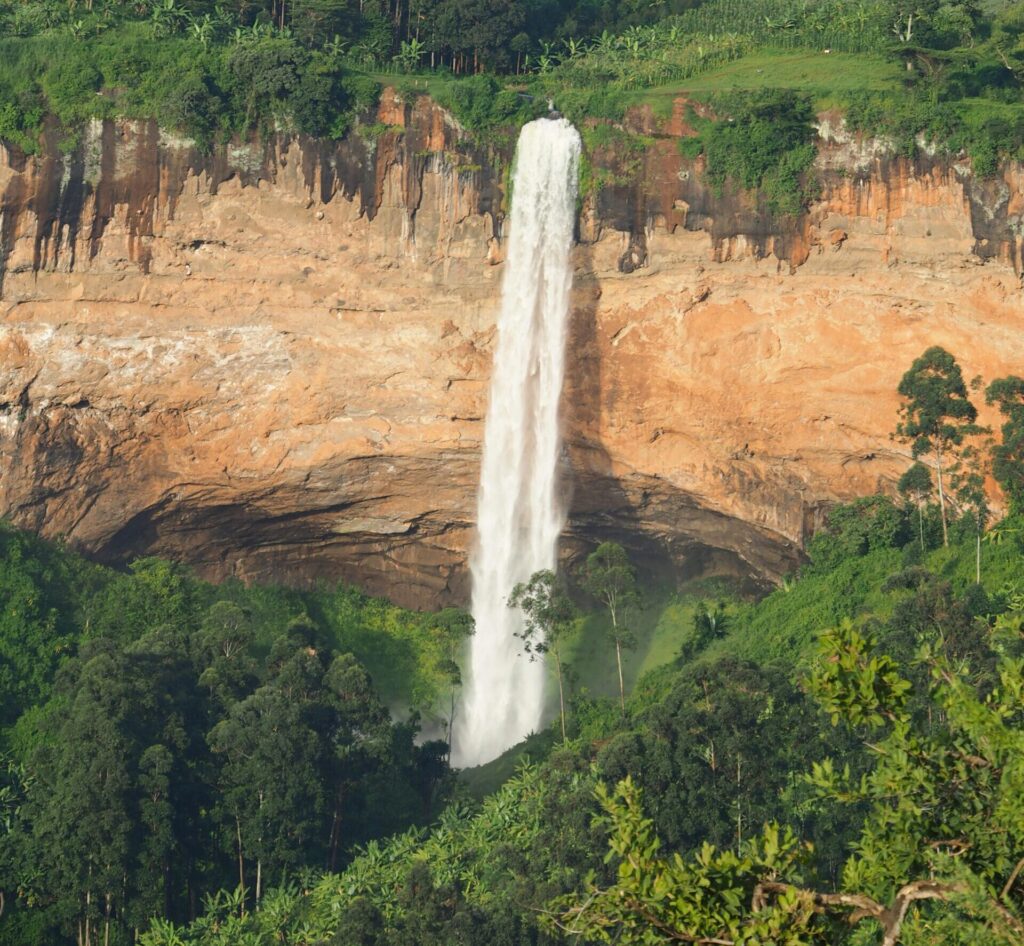 Majestic Sipi Falls cascading down a lush green cliff in Eastern Uganda.